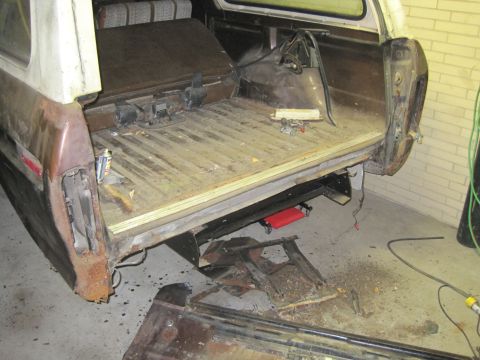 1979 Ford Bronco - The rear cargo area of a vehicle is shown with the tailgate removed and parts scattered around.