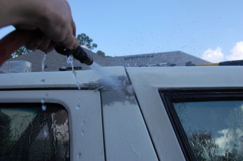 1994 Ford Bronco - Water spraying on the roof seam of a white SUV during a wash.