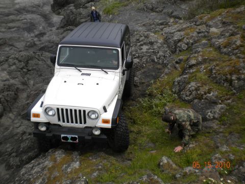 2005 Jeep Wrangler - A white 2005 Jeep Wrangler navigates a rocky path with two people nearby.