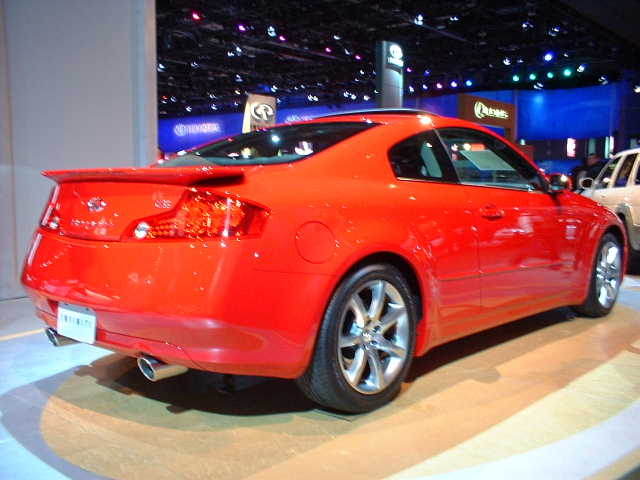 Red coupe with a spoiler and dual exhaust pipes, seen from the rear-left