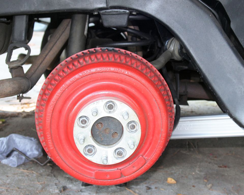 Close-up of a red painted wheel with visible lug nuts and suspension components