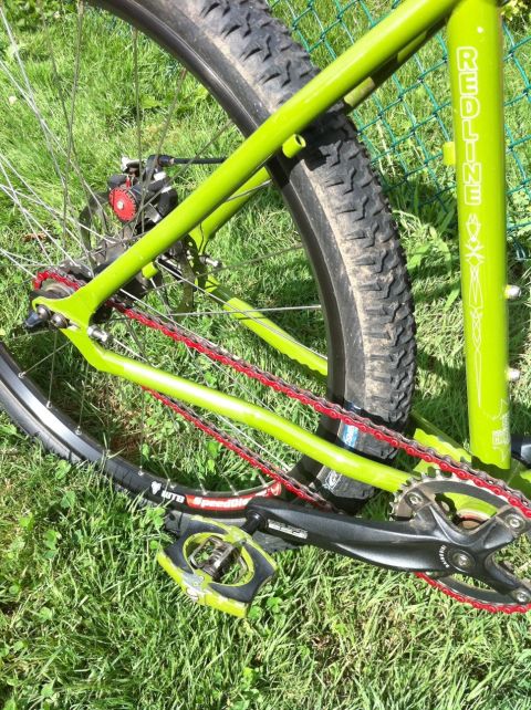 2010 Hyundai Genesis - The frame of a green bicycle is visible, with a red chain and black pedals resting on grass.