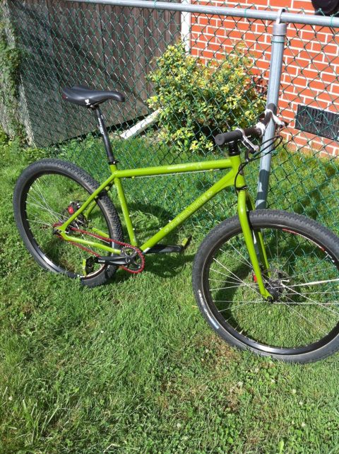 2010 Hyundai Genesis - A green bicycle is parked on grass next to a chain-link fence and brick wall.