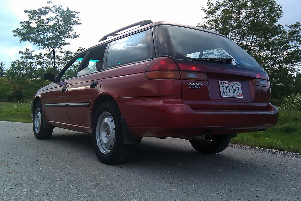 Red 1998 Subaru Legacy wagon with a roof rack and a license plate reading 239-NCT