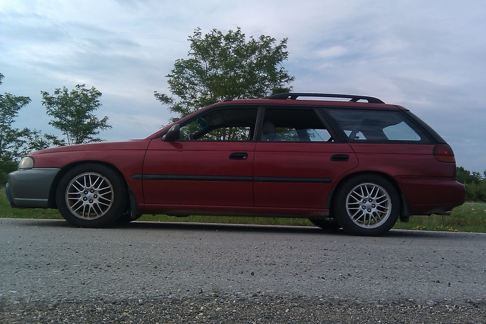 Side view of a red station wagon parked on the side of a road