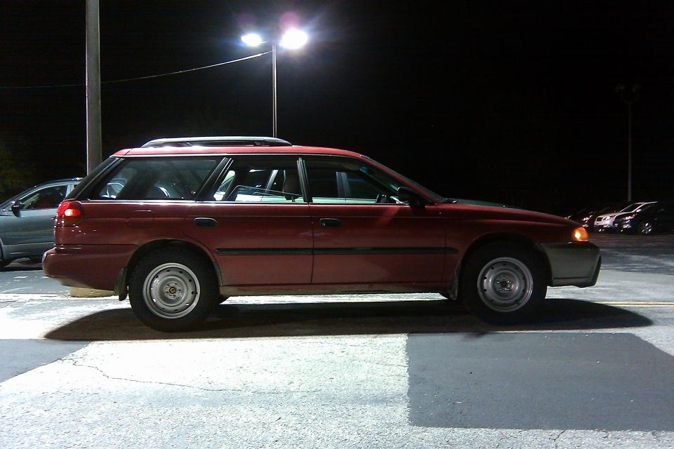 1998 Subaru Legacy station wagon parked at night, side view. Another car is visible to the left