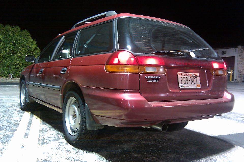 Maroon Subaru Legacy 2.5 GT wagon rear at night with tail lights on and steel wheels