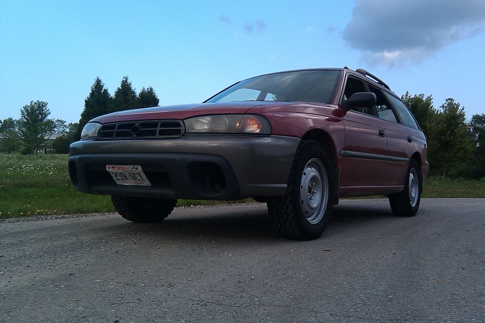 Red 1998 Subaru Legacy wagon lifted on off-road tires, front 3/4 view