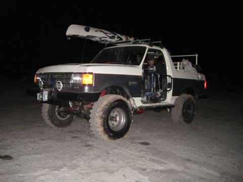 1989 Ford Bronco - This 1989 Ford Bronco, equipped with a roof rack carrying a canoe, is shown at night with its driver's door ajar.