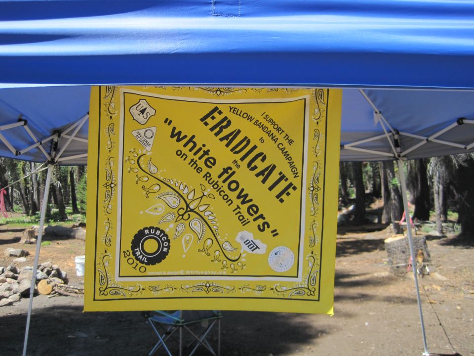 Yellow bandana banner reading Eradicate white flowers on the Rubicon Trail