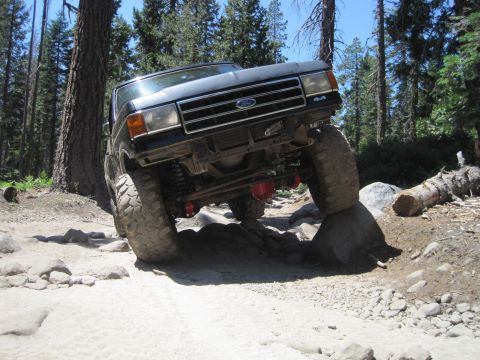 1989 Ford Bronco - This modified Ford Bronco is navigating a rocky off-road trail in a wooded area.