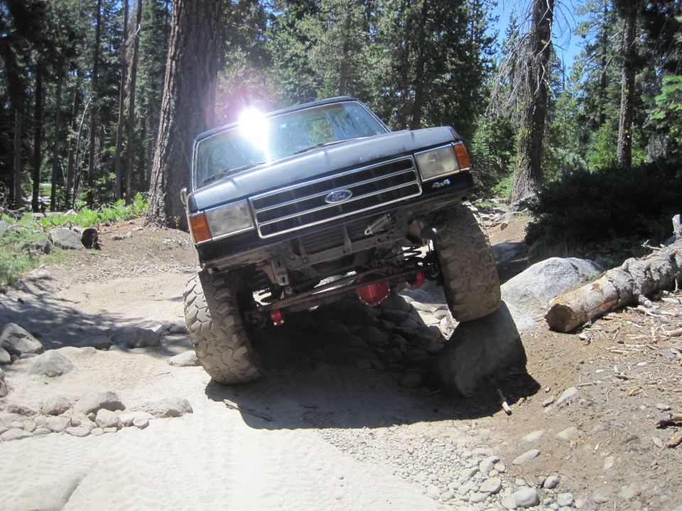 Black Ford Bronco off-roading over rocks, front 3/4 view