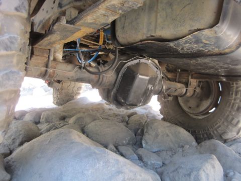 1989 Ford Bronco - Rear axle and suspension components of a 4x4 vehicle are visible, resting on large rocks.