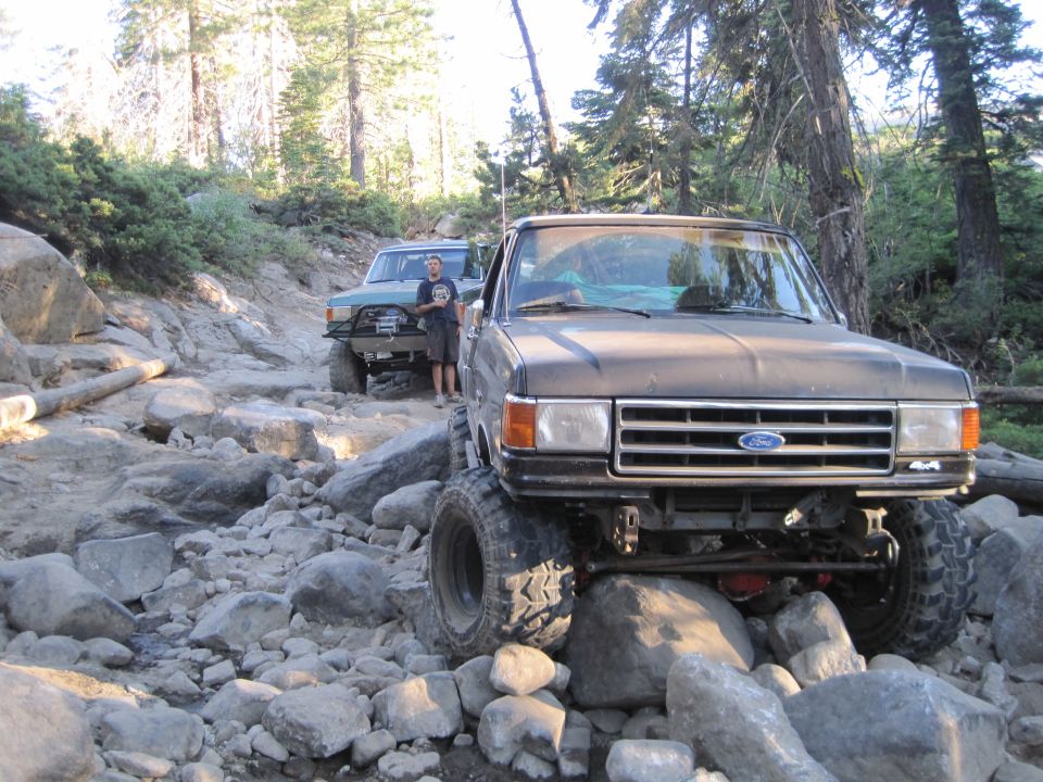 Ford Bronco and another 4x4 truck navigating a boulder-strewn mountain trail