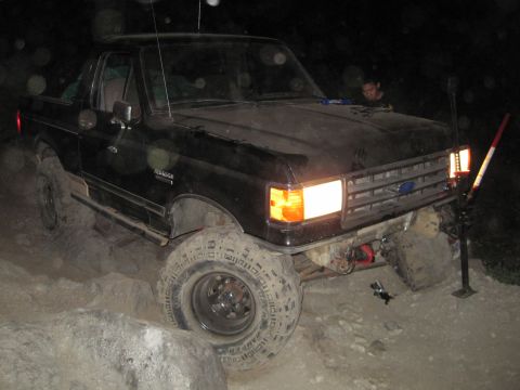 1989 Ford Bronco - This black 1989 Ford Bronco is shown off-roading over rocks and dirt.