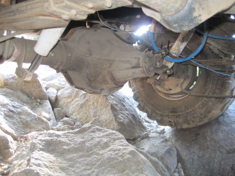 1989 Ford Bronco - The vehicle's undercarriage is shown navigating a rocky terrain, highlighting the rear axle and suspension components.