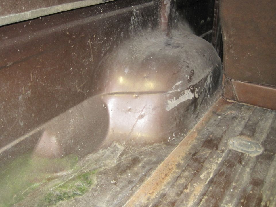 Brown interior of a dusty vehicle, showing wheel well and ribbed floor