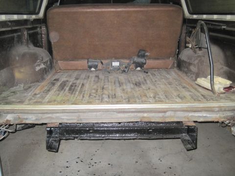 1979 Ford Bronco - Vehicle interior cargo area with a folded brown seat and visible trailer hitch hardware.
