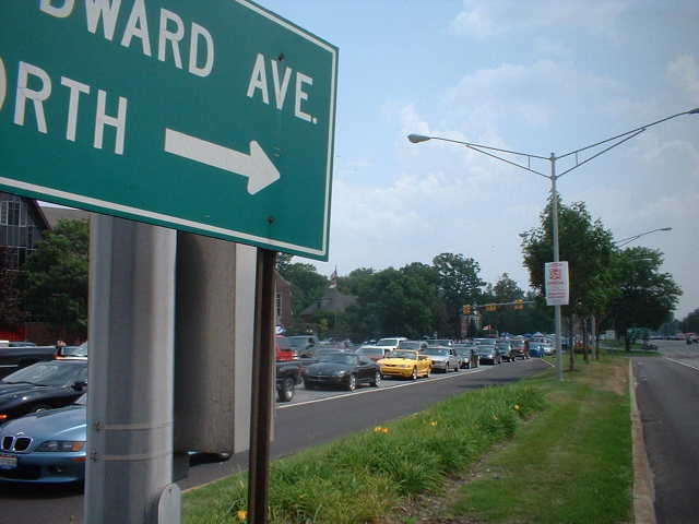 Cars backed up on a road with a green street sign pointing right