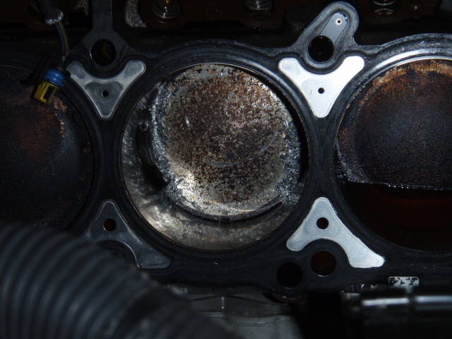 Close-up of an engine cylinder showing a piston with significant wear and damage