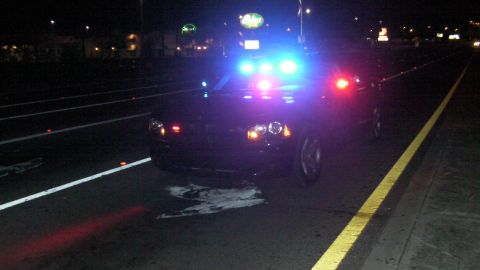 2006 Dodge Charger - A black police car with its emergency lights activated is parked on the side of a road at night.