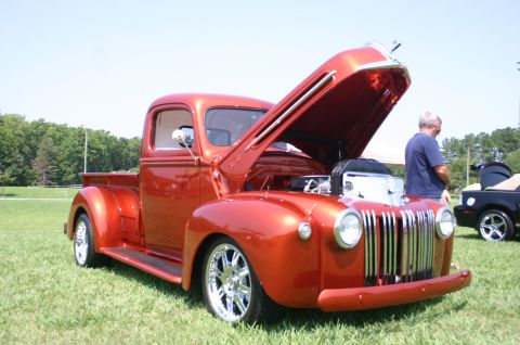 1968 Shelby GT500 - A customized pickup truck with its hood open is displayed on a grassy field on a sunny day.