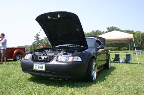 1968 Shelby GT500 - A black Ford Mustang is displayed with its hood open at an outdoor event.