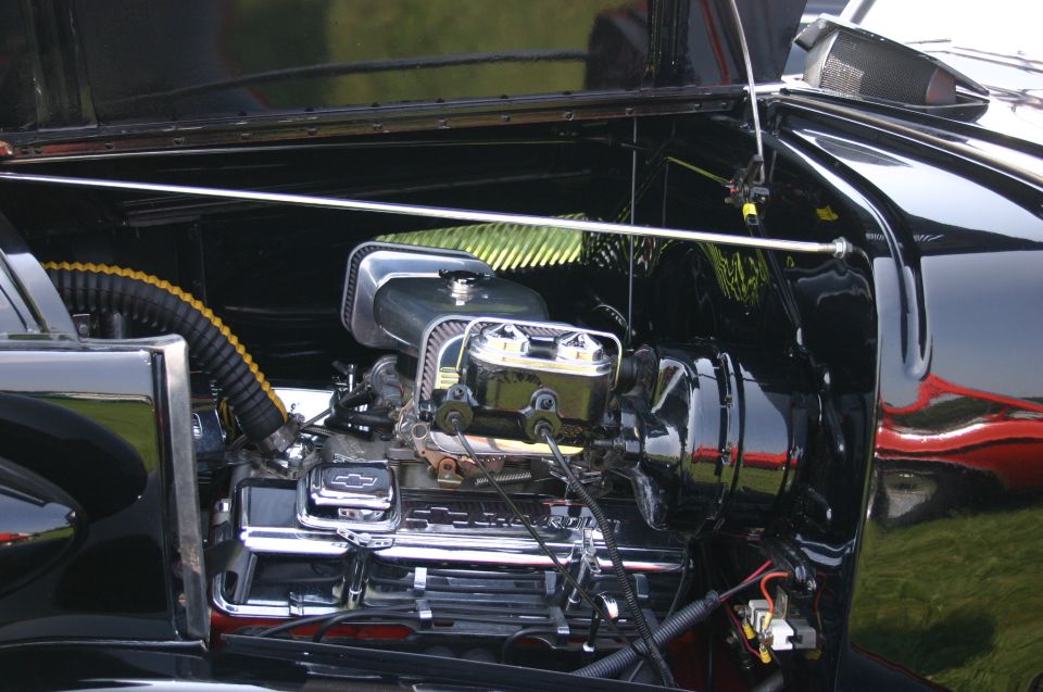 Black car engine bay with chrome details and a Chevrolet V8 engine