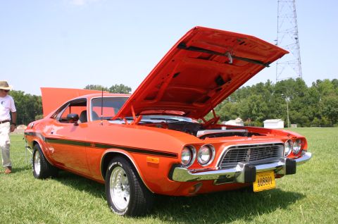 1968 Shelby GT500 - A bright orange 1970 Dodge Challenger R/T is displayed with its hood open at a car show.