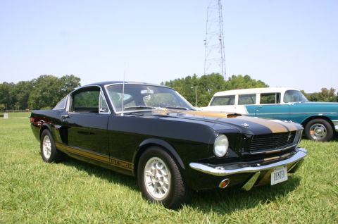 1968 Shelby GT500 - Black 1967 Shelby GT500 with gold stripes is parked on grass next to another vintage car.