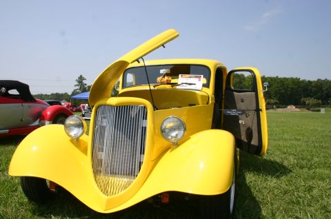 1968 Shelby GT500 - A yellow truck is displayed with its hood and door open at an outdoor event.