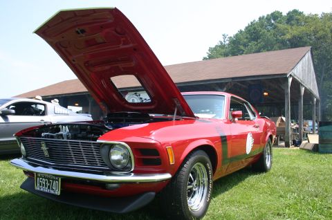 1968 Shelby GT500 - A red 1970 Ford Mustang is parked on grass with its hood open, next to another vehicle under a covered structure.