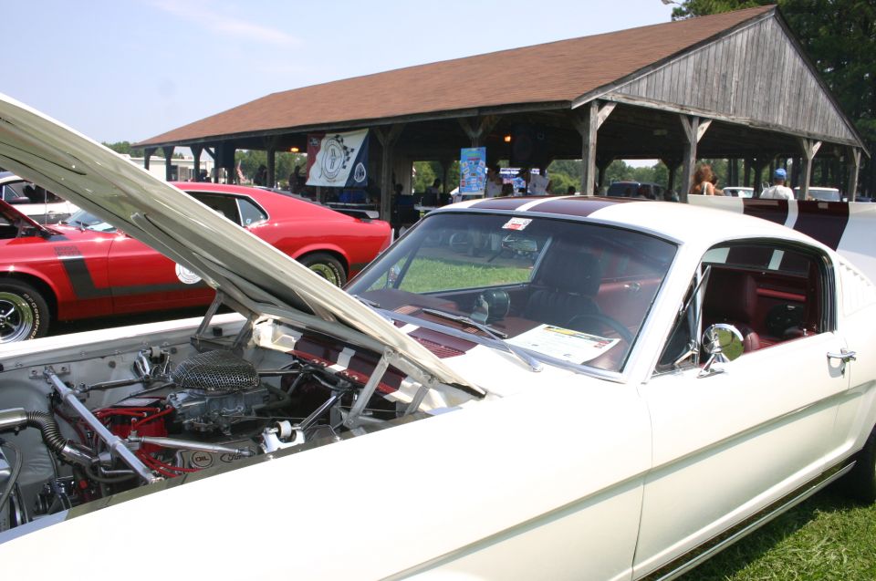 White Ford Mustang with hood open, red car behind it