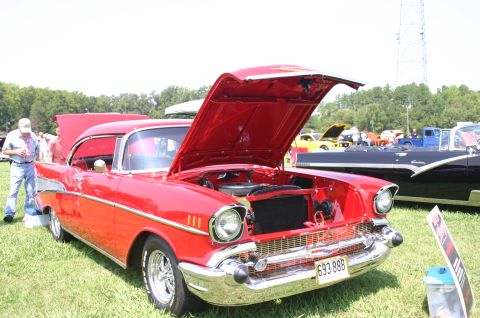 1968 Shelby GT500 - A red 1957 Chevrolet Bel Air is displayed with its hood open at an outdoor car show.
