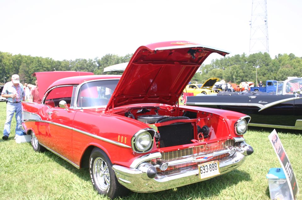 Red 1957 Chevrolet Bel Air with hood open, license plate 693-888. Other cars visible in background