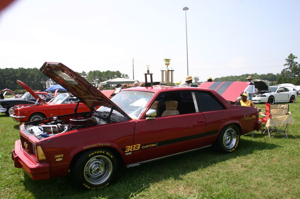 Red coupe with hood open, "333 CUSTOM" text on door, Goodyear Futura GLS tires. Other cars and trophies visible