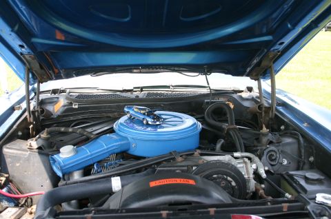 1968 Shelby GT500 - The engine bay of a blue muscle car from the 1970s, a toy car atop the air cleaner assembly.