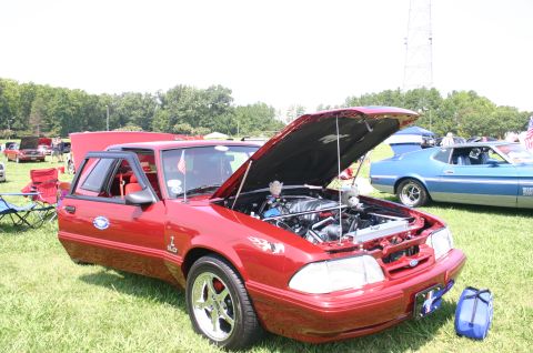 1968 Shelby GT500 - Red 1987 Ford Mustang GT and blue 1971 Ford Mustang Mach 1 at a car show.
