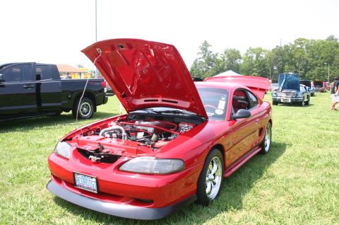 1968 Shelby GT500 - A red Ford Mustang is displayed with its hood open at an outdoor car show.