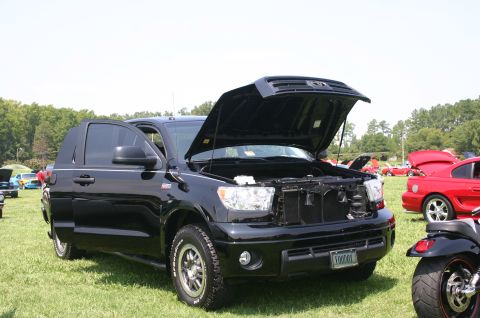 1968 Shelby GT500 - A black Toyota Tundra truck is displayed with its hood and driver's door open at an outdoor car show.