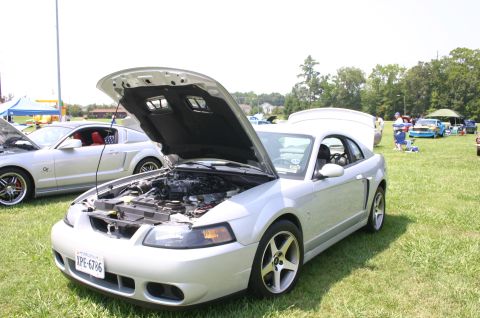 1968 Shelby GT500 - A silver Ford Mustang is displayed with its hood open at an outdoor car show.