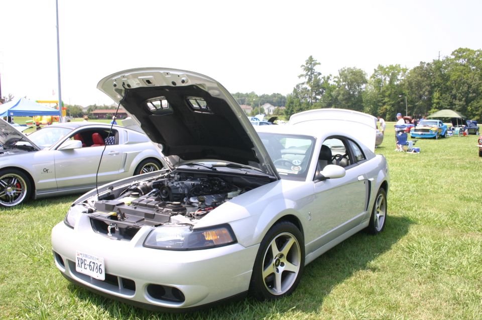 Silver Ford Mustang with hood open, showing engine. License plate reads YPE-6786. Another silver Mustang is parked behind it