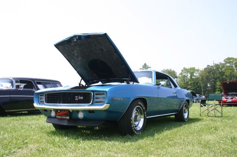 1968 Shelby GT500 - A blue 1969 Chevrolet Camaro Z/28 is displayed with its hood open at an outdoor car show.