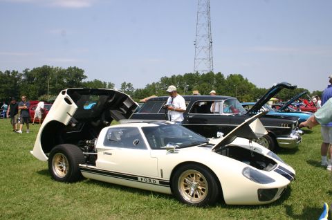 1968 Shelby GT500 - A white Ford GT40 is displayed with its front and rear hoods open at a car show, with other classic cars in the background.