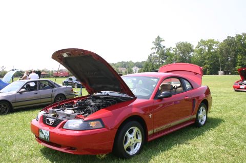 1968 Shelby GT500 - A red coupe with its hood and trunk open sits on a grassy field at a car show.