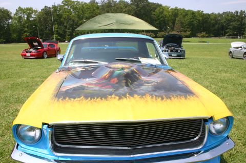 1968 Shelby GT500 - A blue 1968 Mustang with a custom painted hood flames and artwork is displayed at a car show.