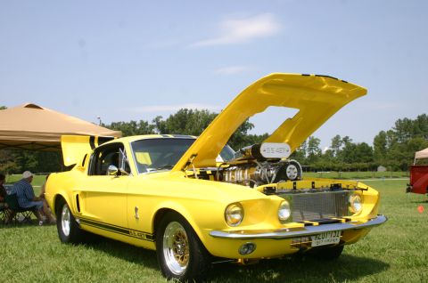 1968 Shelby GT500 - A bright yellow 1968 Shelby GT500 is displayed with its hood open, revealing a powerful engine and custom details.