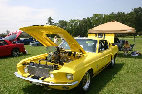 1968 Shelby GT500 - A yellow 1967 Shelby GT500 with its hood open, revealing a supercharged engine, at a car show.