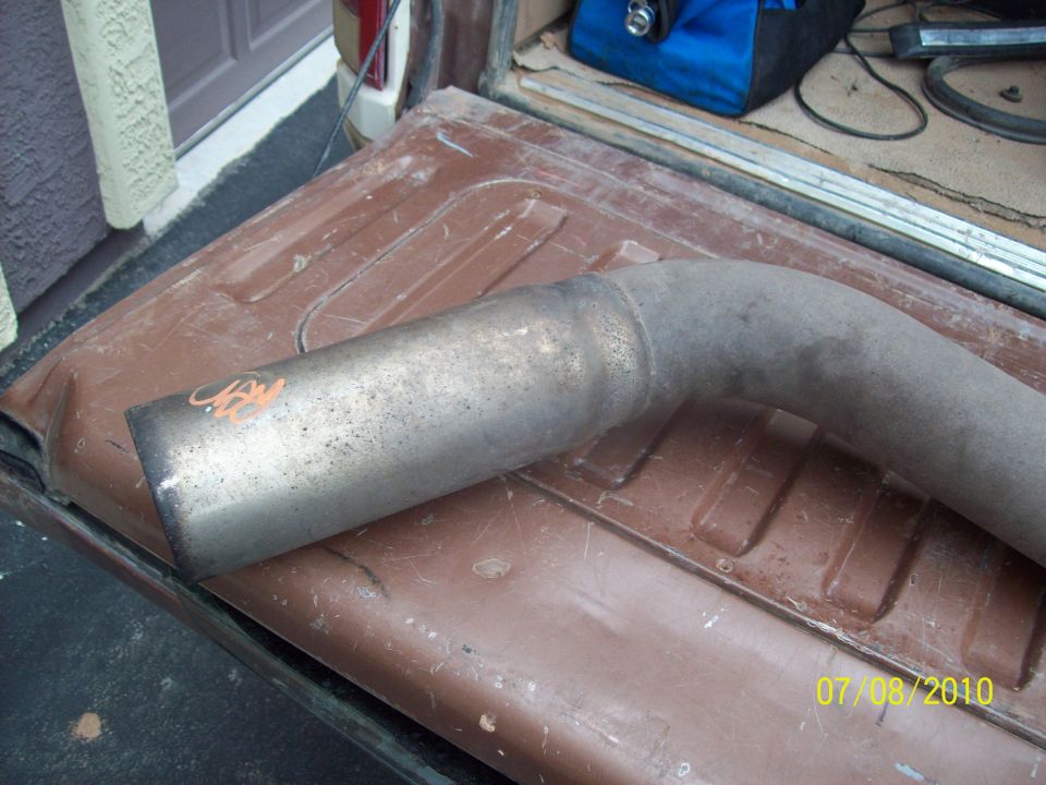 Exhaust pipe with orange markings, lying on a brown truck bed