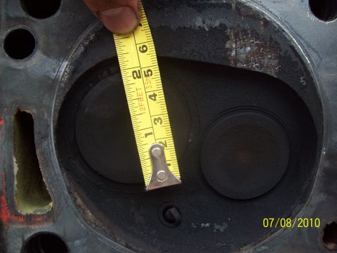 1985 Ford Bronco - A yellow measuring tape is used to measure the opening of an engine cylinder head, with a date stamp visible in the corner.